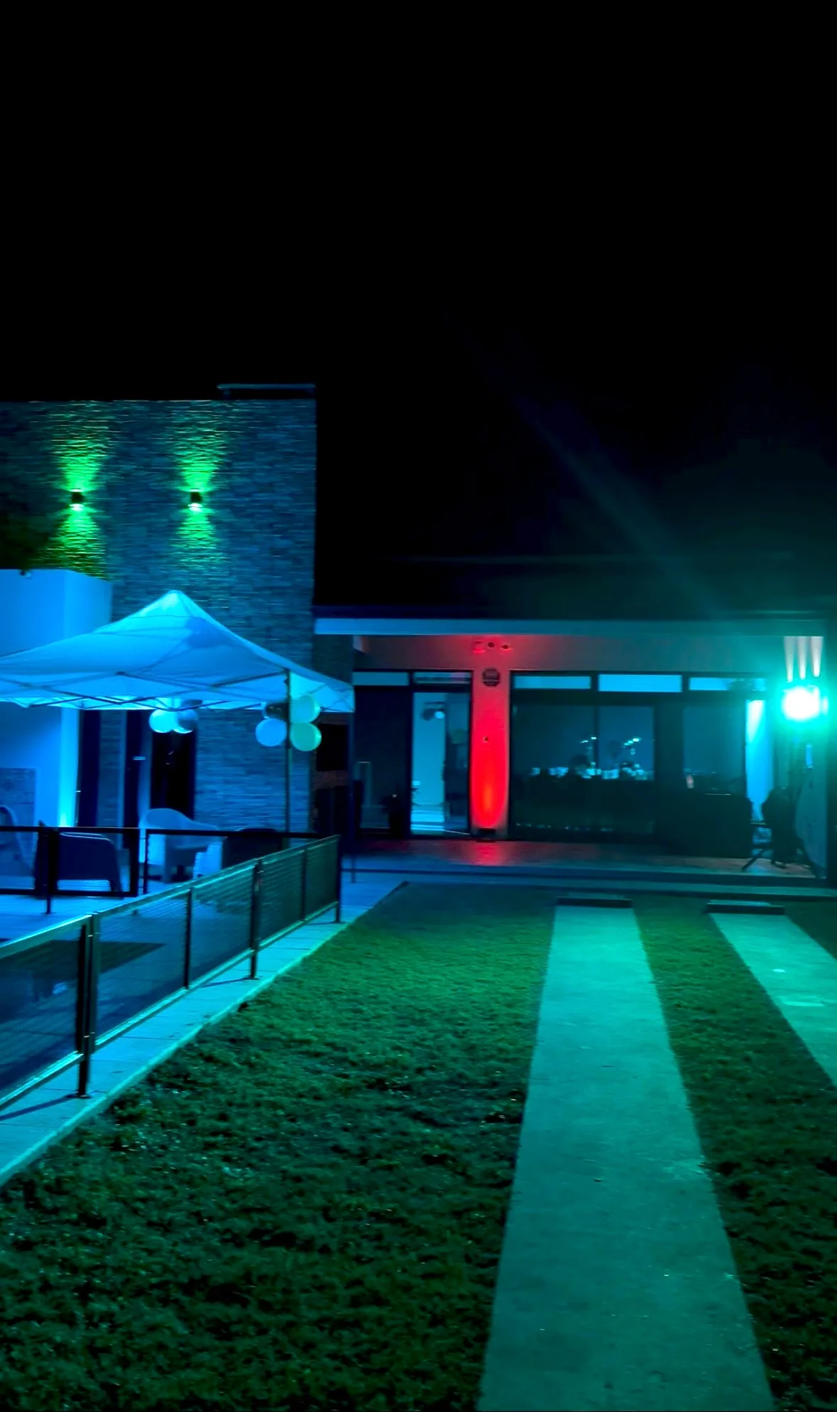 Parque y entrada de un salón iluminados en celeste