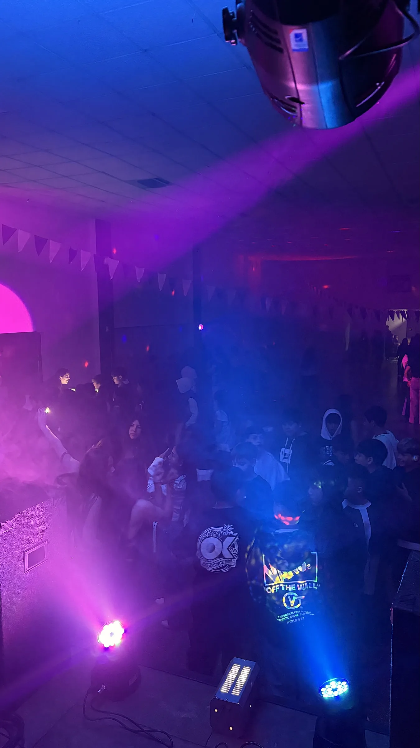 Haces de luz magenta y azul cruzando la pista llena de gente