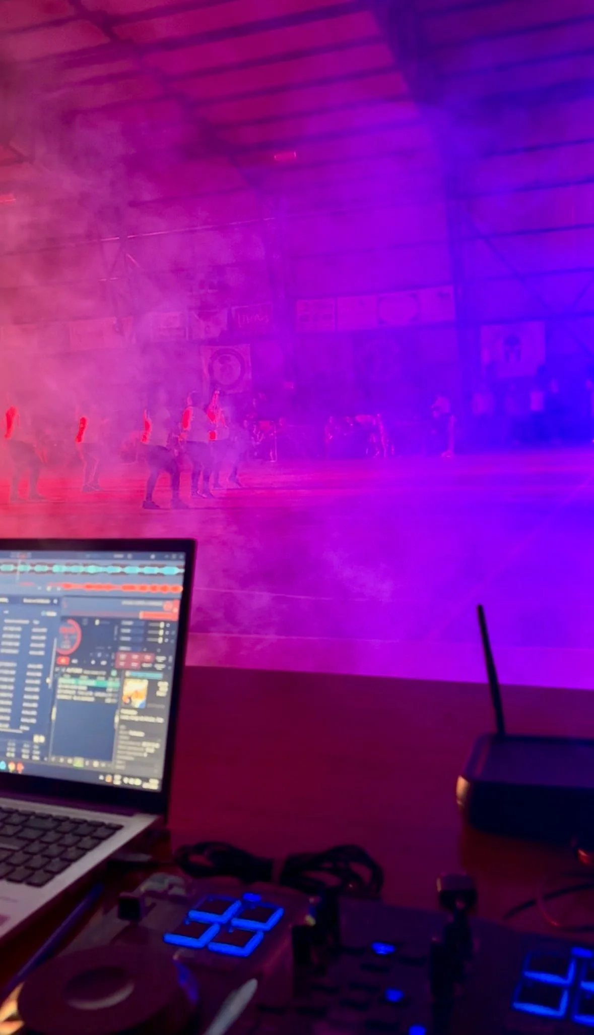 Cabina del DJ con controlador y humo magenta de fondo