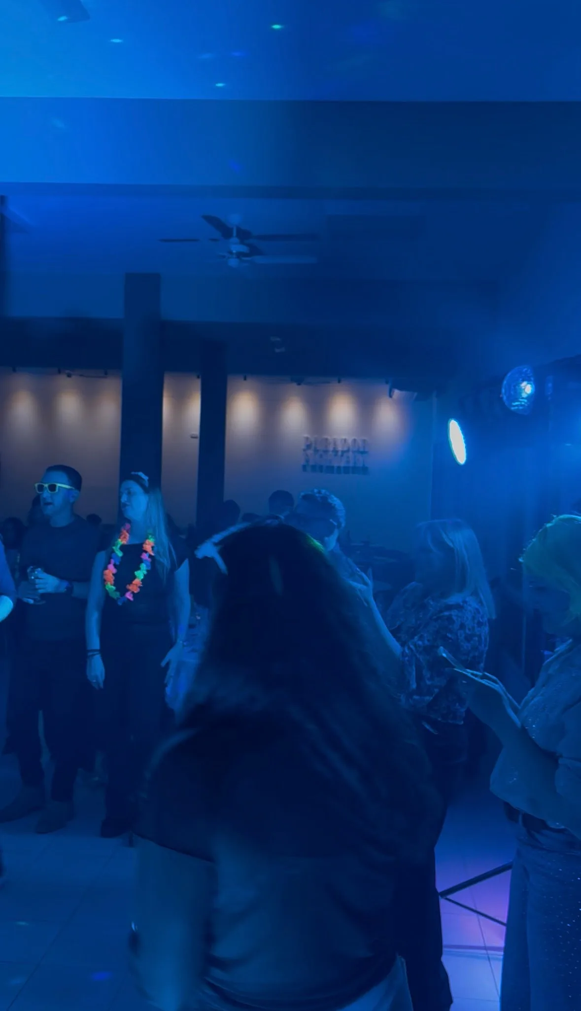 Gente bailando en un salón con luces azules